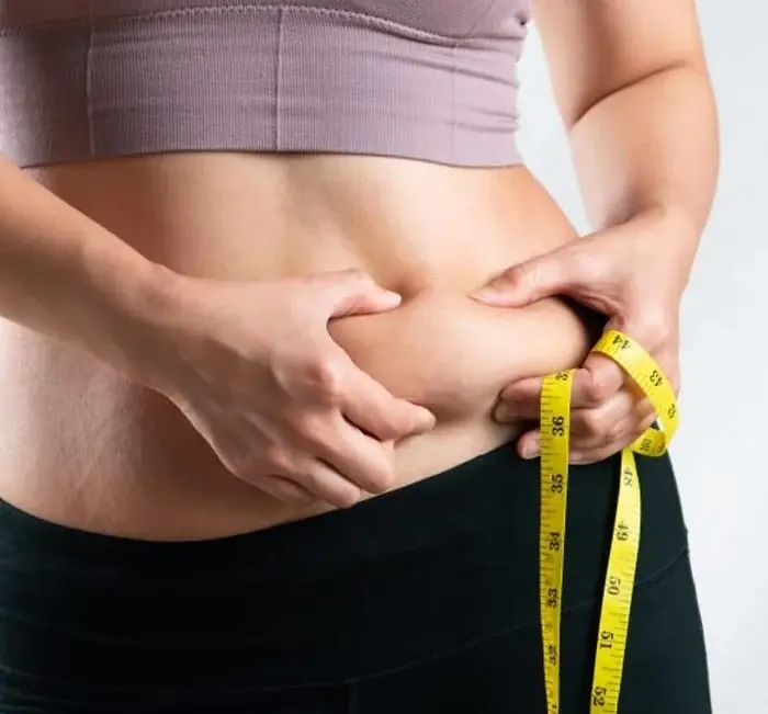 Person measuring their waistline, illustrating why fat loss shows on a weekly trend rather than day to day